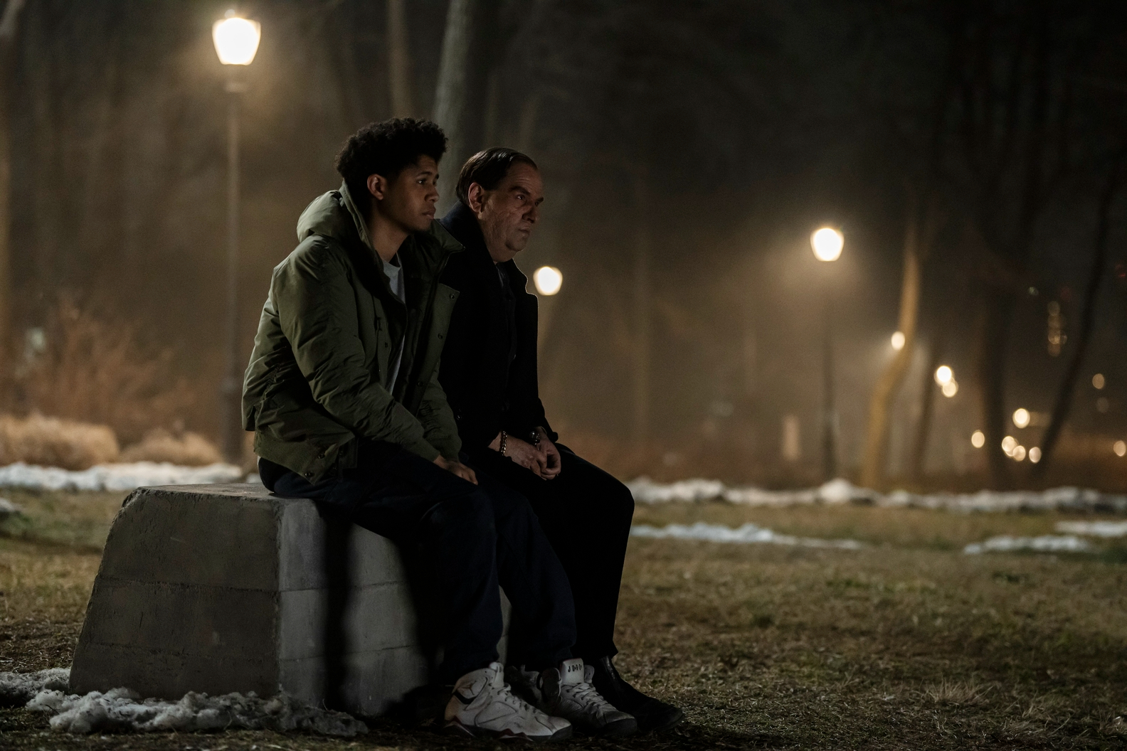 Rhenzy Feliz and Colin Farrell sit on a stone bench together in The Penguin.