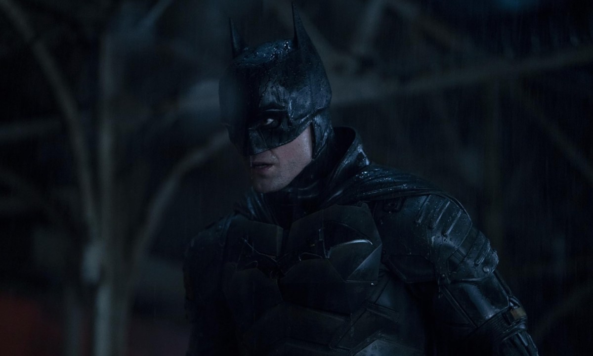 Batman stands and stares in the rain.