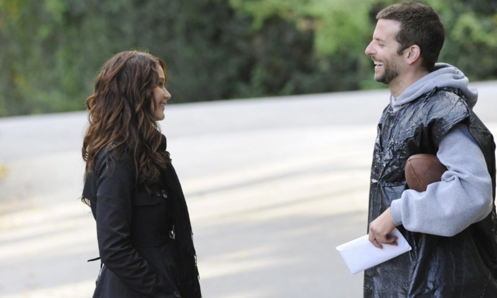 A man wearing a garbage bag stands across from a girl.