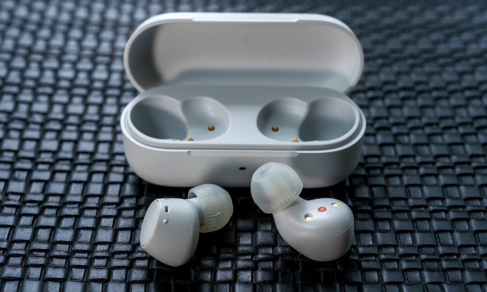 Sony WF-C510 loose earbuds in front of open case.