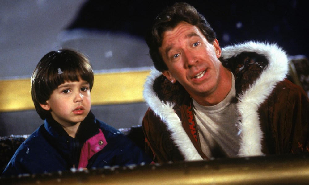 Tim Allen sits in a sleigh with a boy.