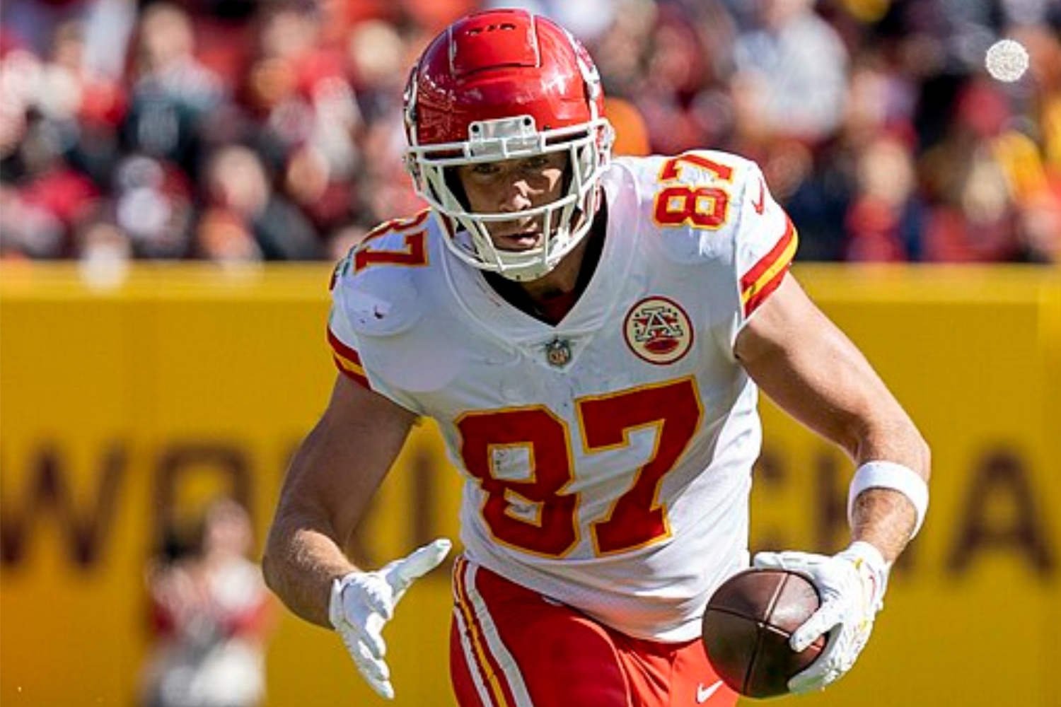 Travis Kelce tient le ballon d'une main et court.