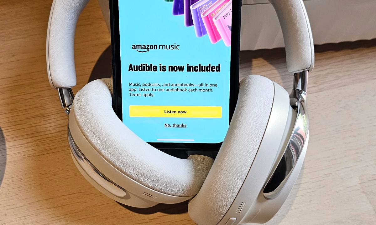 An iPhone with Bose headphones showing the Amazon Music app with a promotional message for Audible audiobooks.