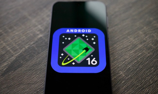 The Android 16 logo on a smartphone, resting on a shelf.