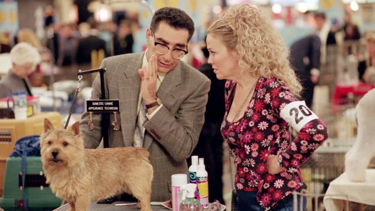 In „Best in Show“ flüstert ein Mann einer Frau zu.