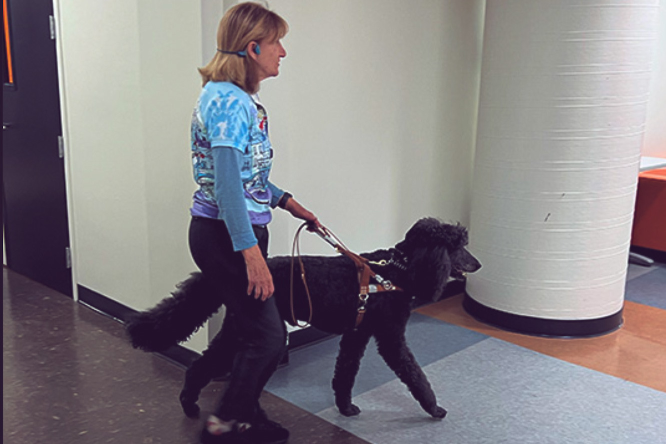 Uma mulher cega passeando com um cachorro em um prédio.