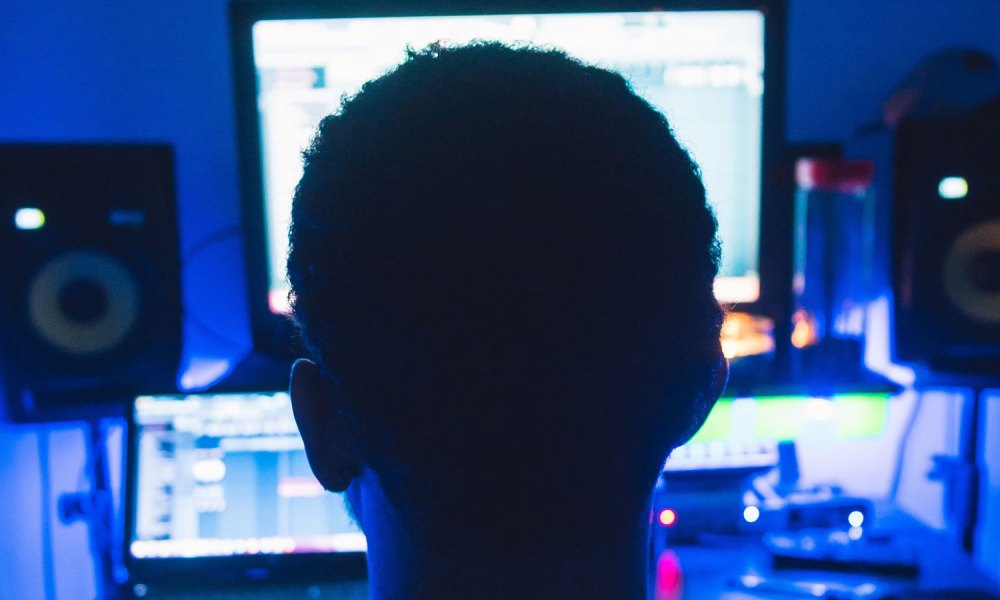 Man sitting in front of a monitor in the dark.