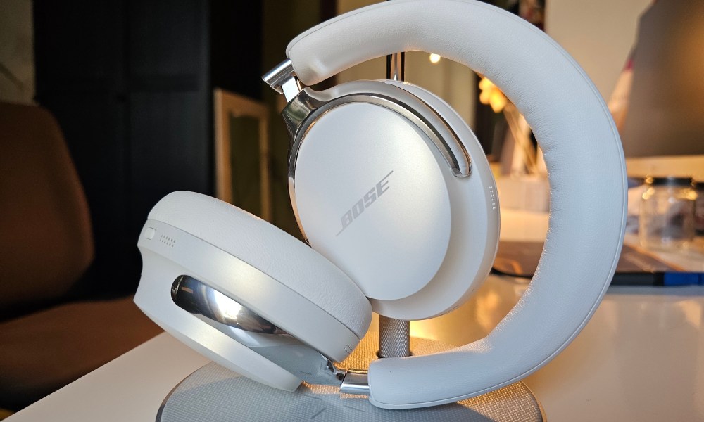 The Bose QuietComfort Ultra Headphones in Diamond color resting against a headphones stand.