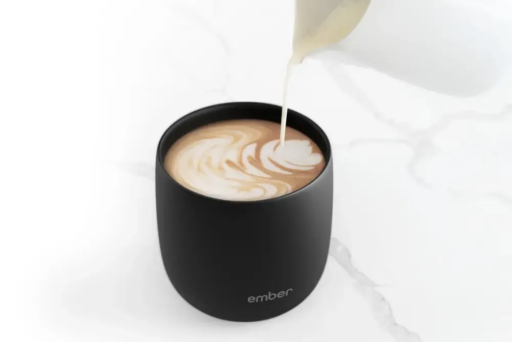 Der Ember Temperature Control Smart Cup mit eingefülltem Milchkännchen.