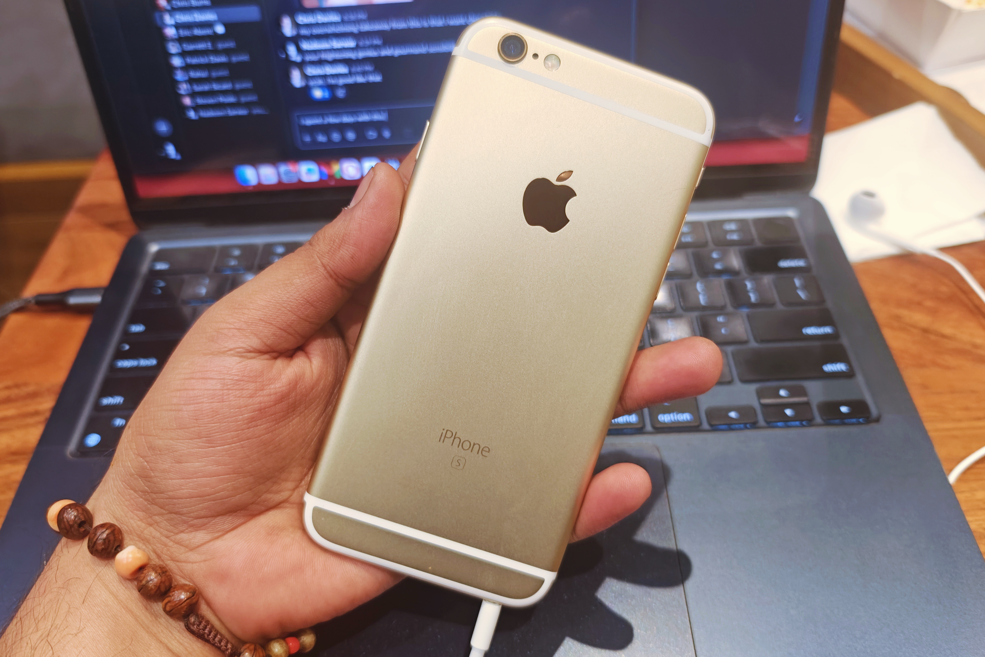 A gold iPhone 6S in the hands of a user.