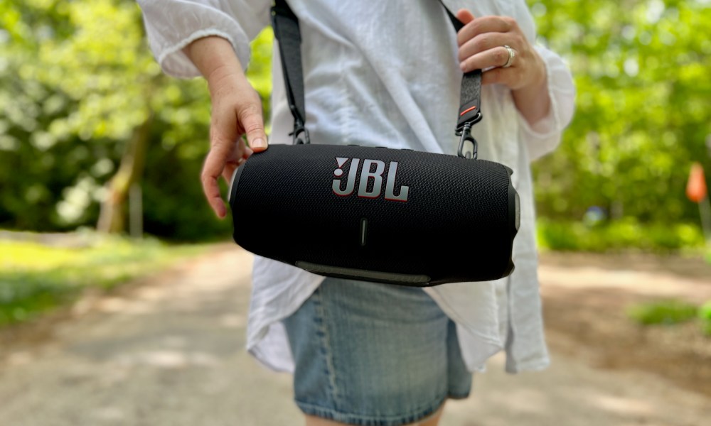 The JBL Xtreme 4 Bluetooth speaker on its shoulder strap.