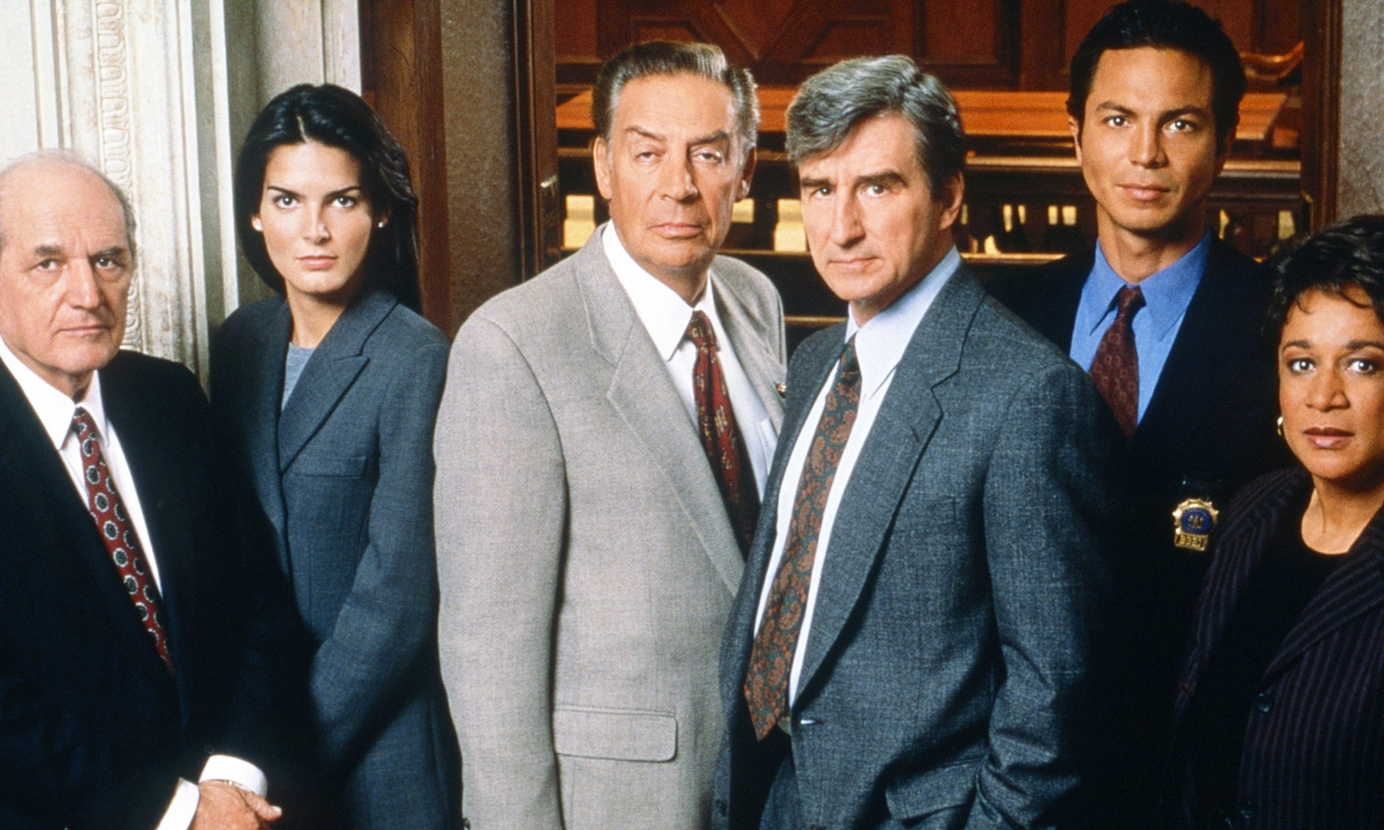 The original cast of Law & Order posing in an office.