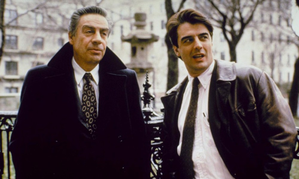 Two men stand in the street in suits in a scene from Law & Order.