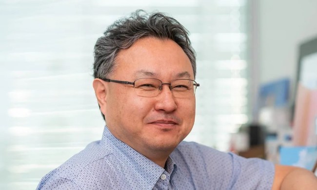 Shuhei Yoshida posing in a home. He's wearing a blue button-up shirt.