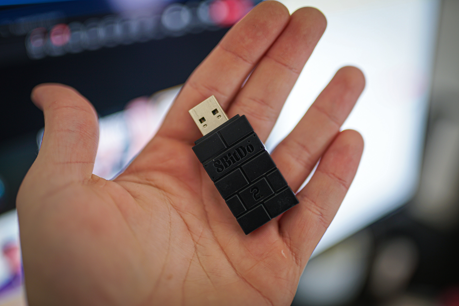 O adaptador USB sem fio 8BitDo 2 na mão.