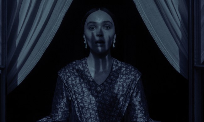 A clawed hand's shadow covers Lily-Rose Depp in Nosferatu.