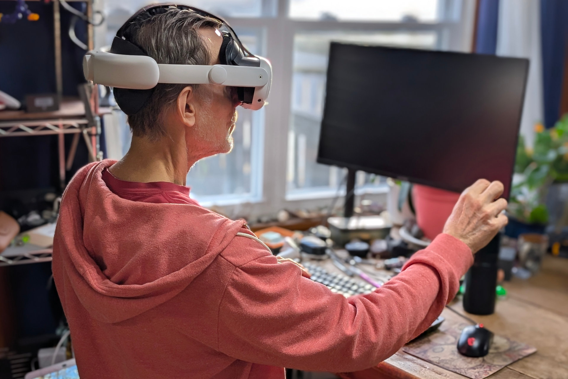 Alan Truly senta na frente de um PC com Windows e ajusta uma tela virtual enquanto usa um headset Meta Quest 3 VR.