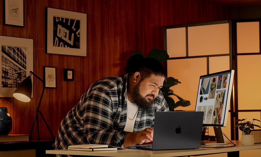 A person using a MacBook with an Apple Studio Display.