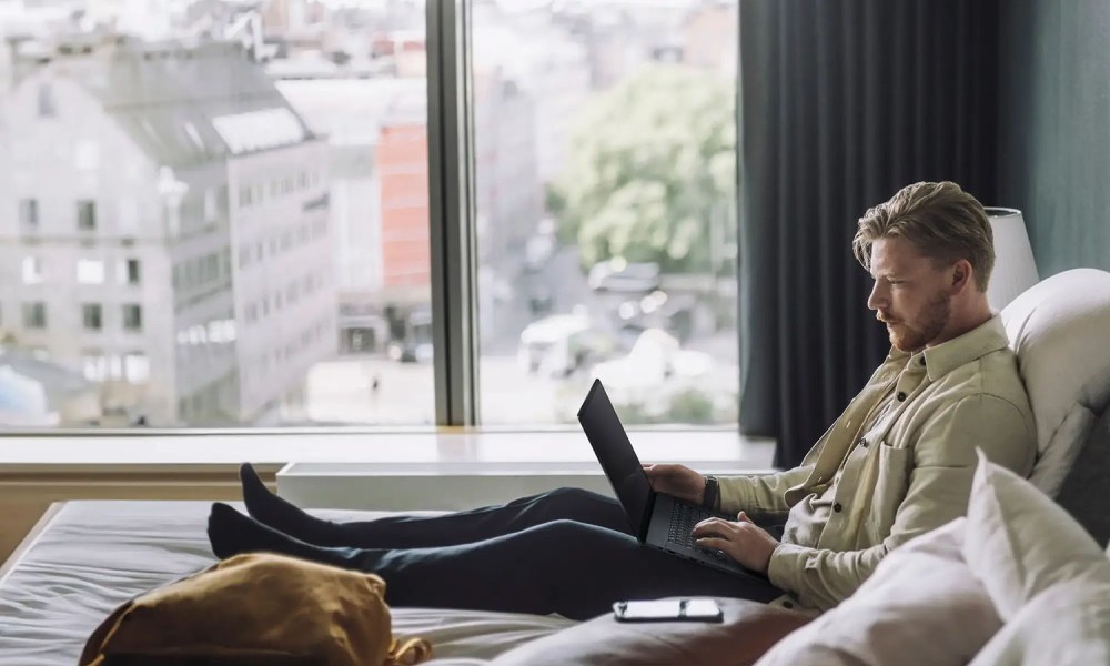 A man using the Asus ProArt P16 laptop while sititng on a bed.