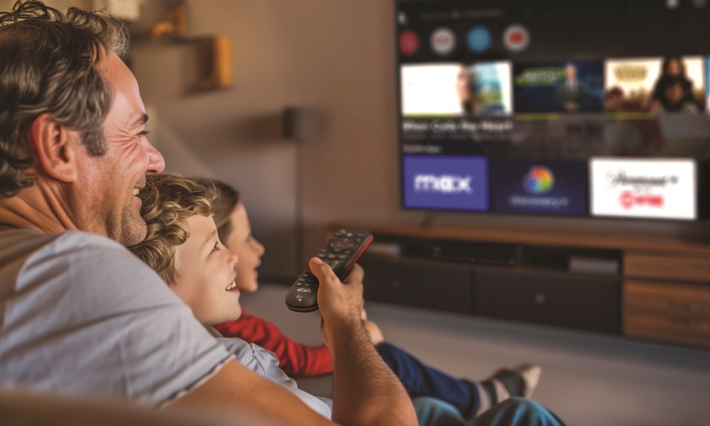 Dad with kids in living room watching Sling