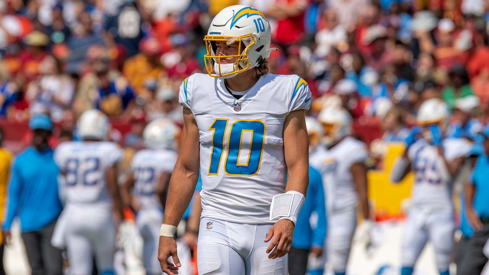 Justin Herbert caminhando no campo de futebol dos Chargers.