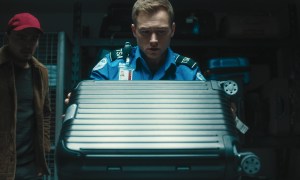 A man looks at a suitcase in Carry-On.