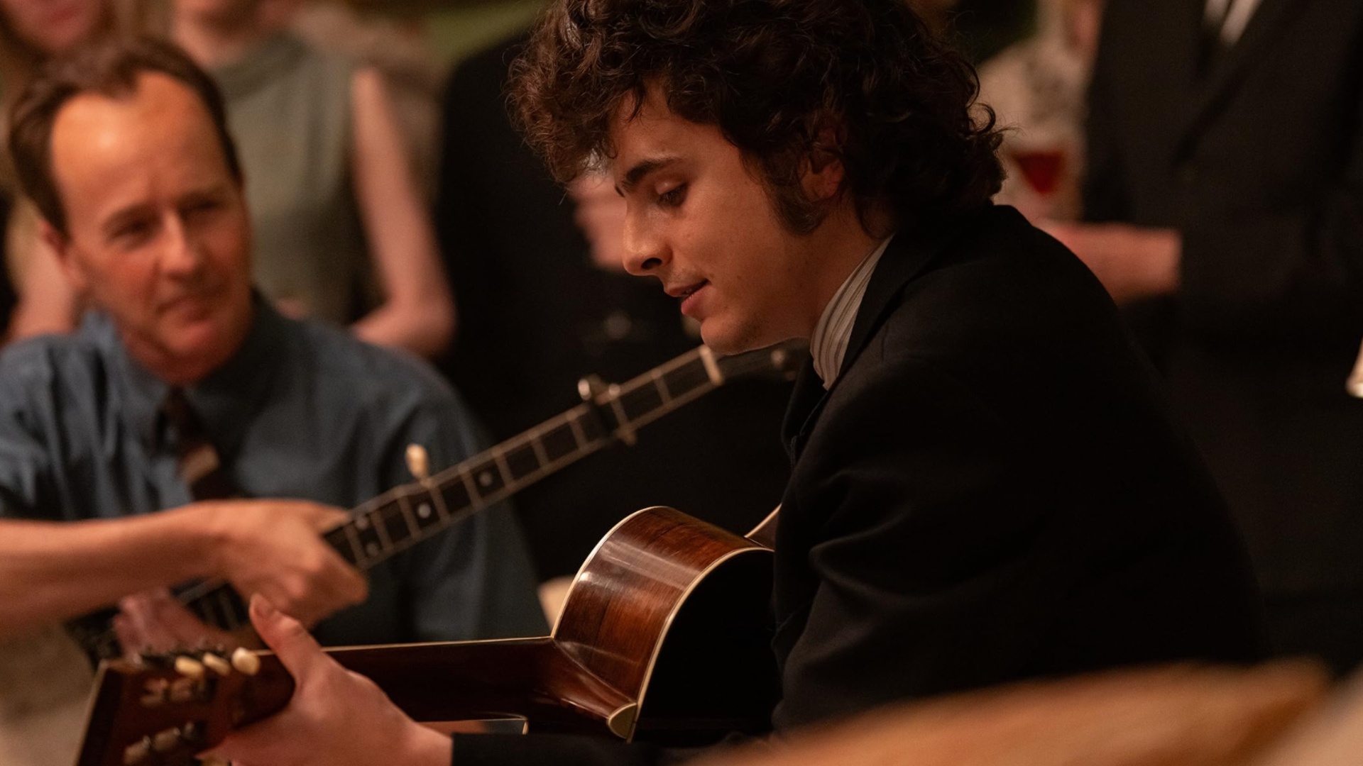 Timothee Chalamet segura um violão e toca em A Complete Unknown.