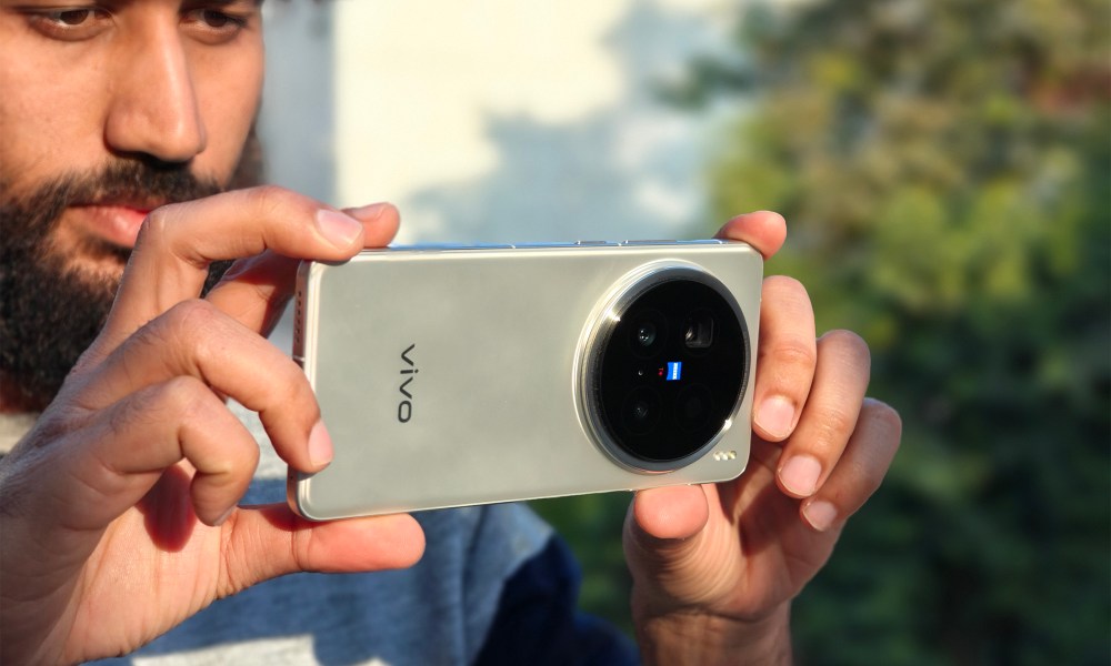 Man holding Vivo X200 Pro with Zeiss lenses up to his face.