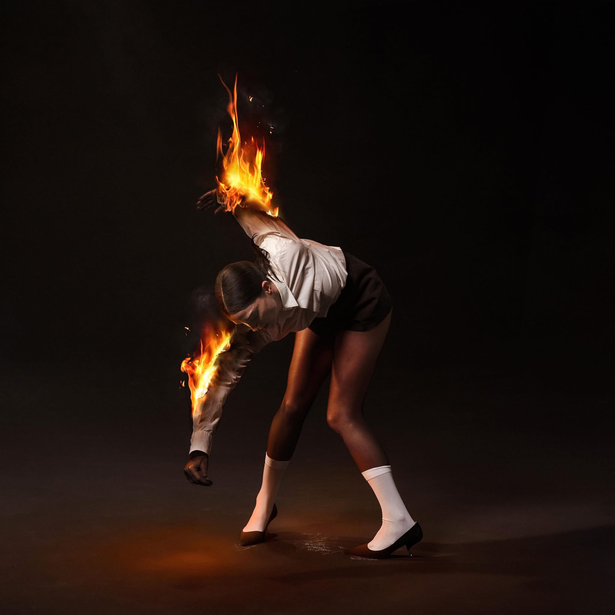 The artwork on the St. Vincent album All Born Screaming or a woman bent over with her arms on fire.