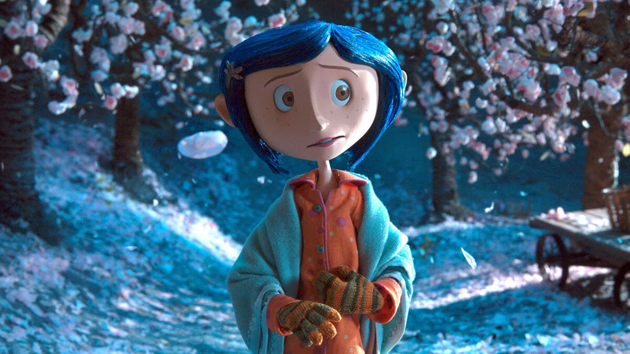 Eine Stop-Motion-Animationsfigur mit blauen Haaren, die in einer schneebedeckten Gegend draußen in Coraline steht.