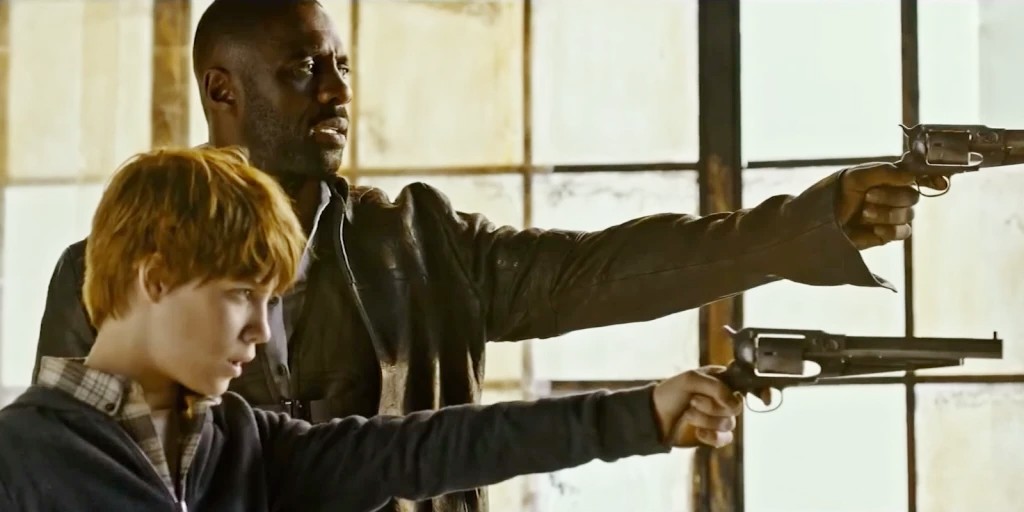 A man and a boy aim their guns in The Dark Tower.