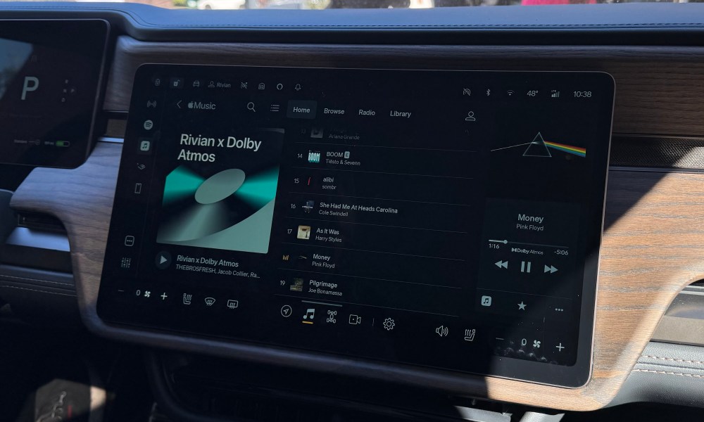 The center console touchscreen in a Rivian R1S displaying Dolby Atmos Music tracks on Apple Music.