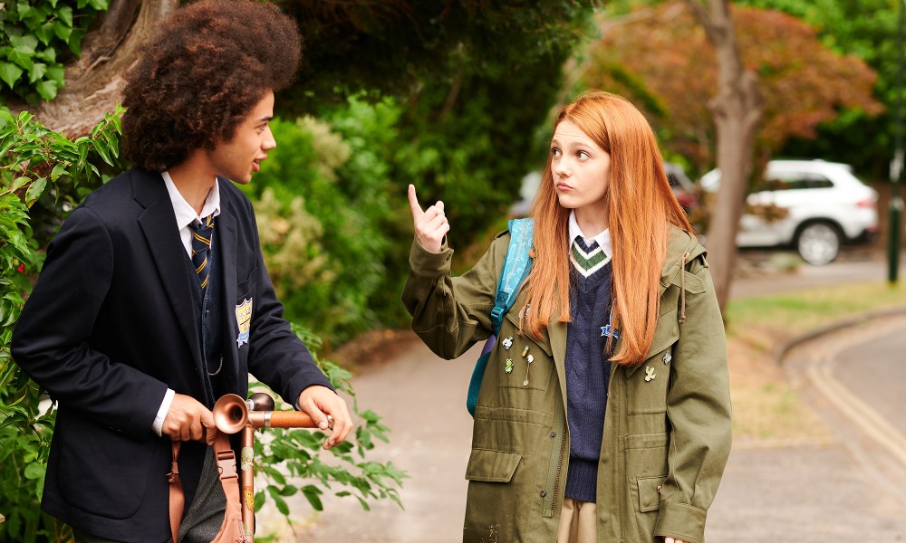 A young redhead woman talking with a young man on a bicycle with a large afro in Geek Girl.