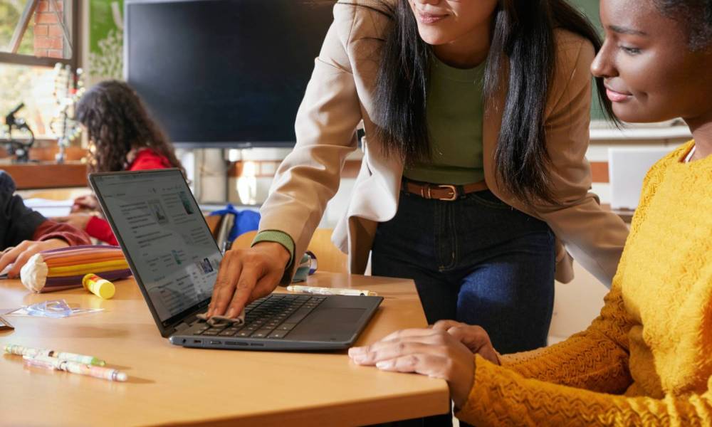 A student and teacher using a Chromebook on a desk.