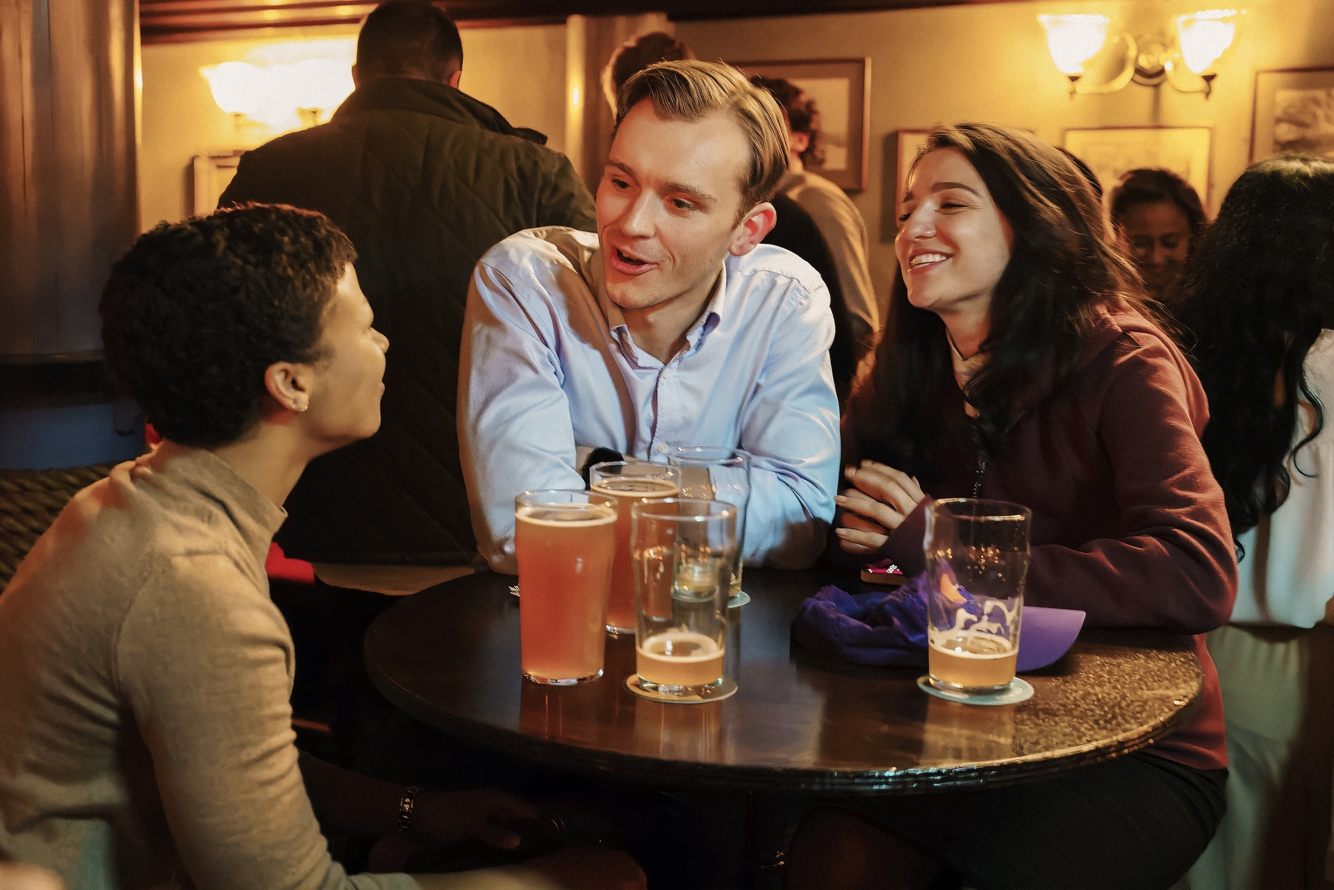 Three people stand at a table and laugh in Industry.