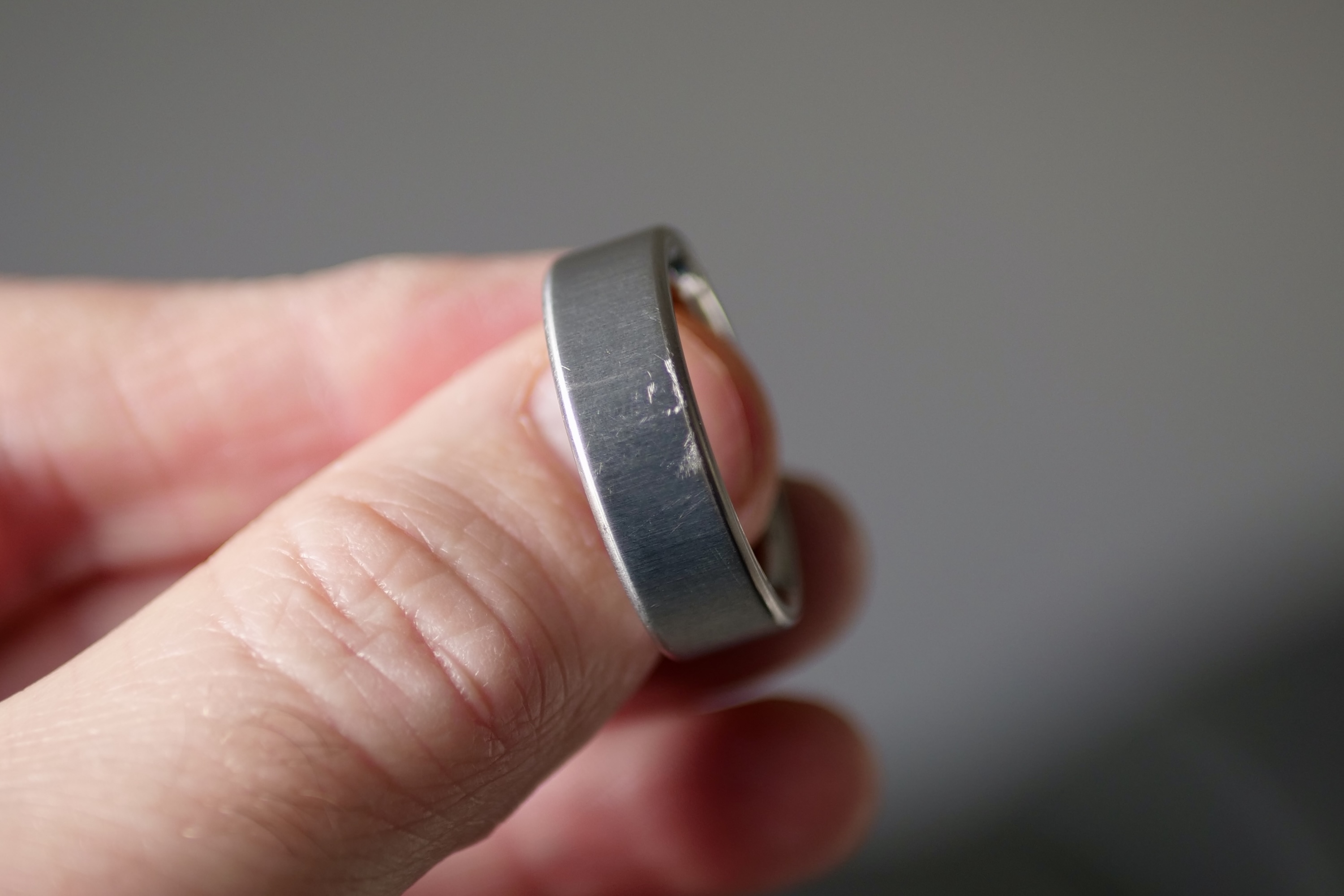 A person holding the Oura Ring 4, showing surface scratches.