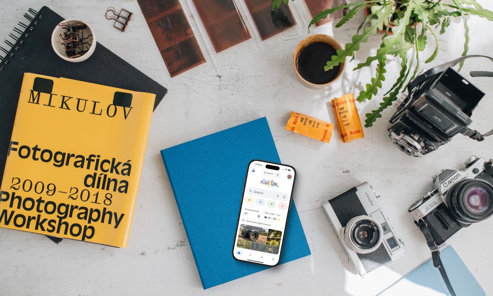 An iPhone on a table next to a camera showing the Google app.