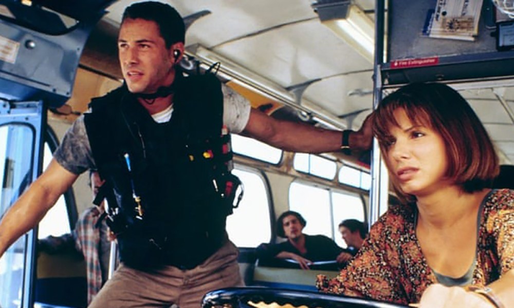 Keanu Reeves wearing a vest while Sandra Bullock rides a bus in Speed.