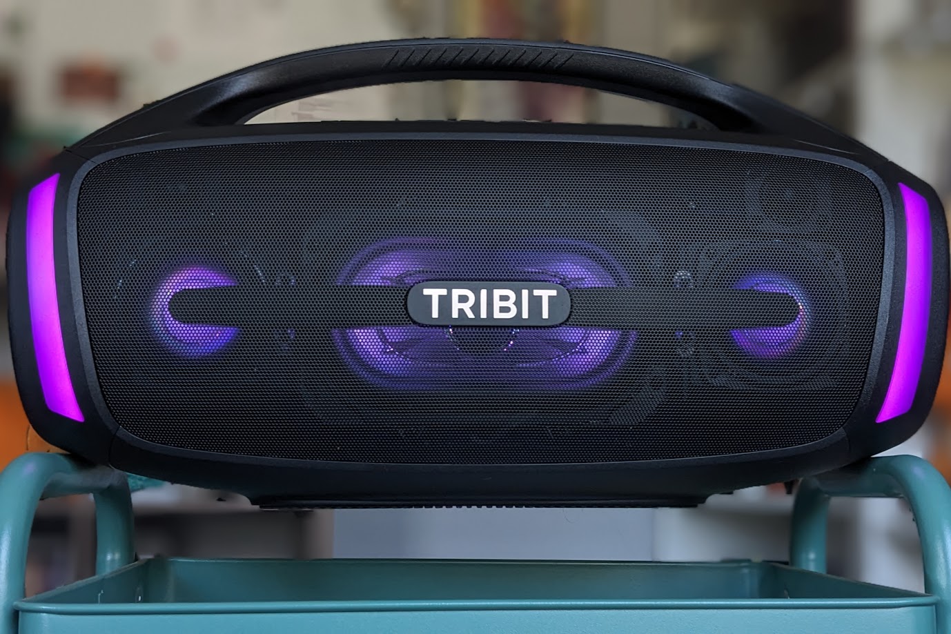 L'enceinte Tribit StormBox Blast 2 en équilibre sur un chariot. Ses lumières LED sont allumées en violet.