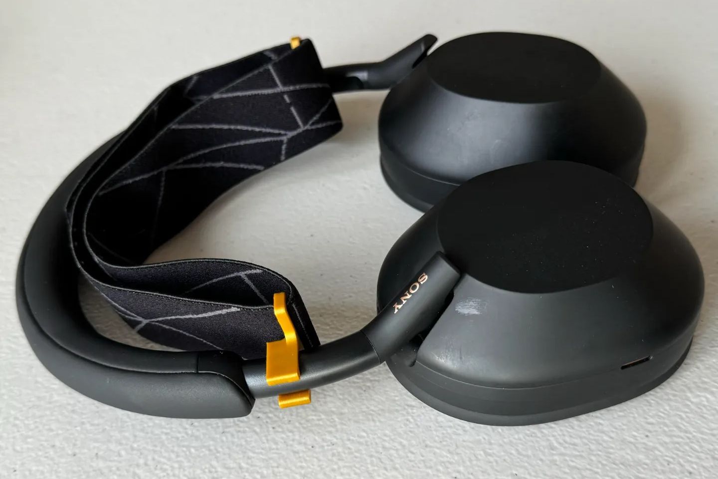 Un ensemble de supports de bandeau imprimés en 3D avec un bandeau SteelSeries Arctis de remplacement, fixé à un ensemble d'écouteurs Sony WH-1000XM5.