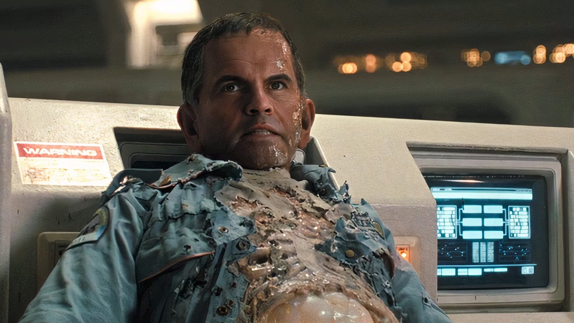 A hideous half-digital avatar of Ian Holm stares uncannily in a shot from the movie Alien: Romulus.