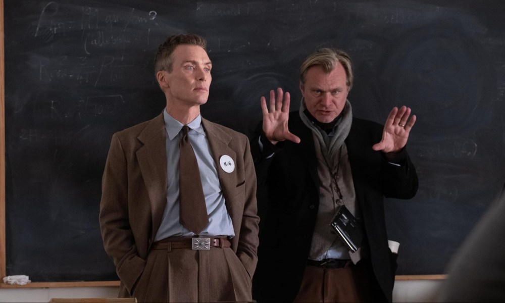 Christopher Nolan puts his hands up next to Cillian Murphy in Oppenheimer.