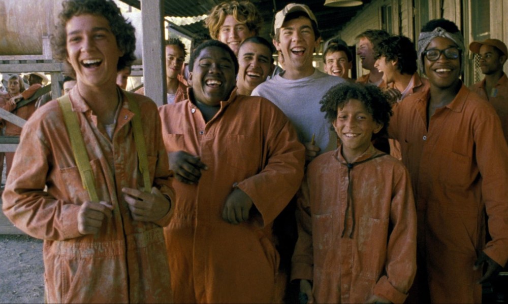 A group of boys in orange jumpsuits stand together in Holes.