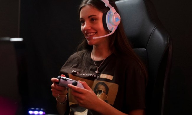 A woman with the PS5 controller wearing the JBL Quantum 910P gaming headset.