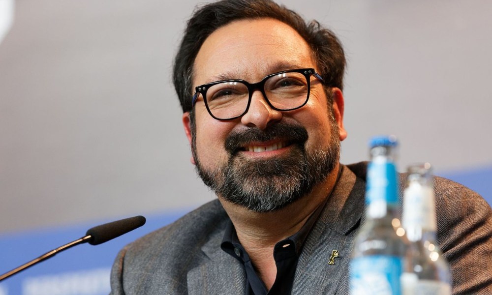 James Mangold smiles at the podium.