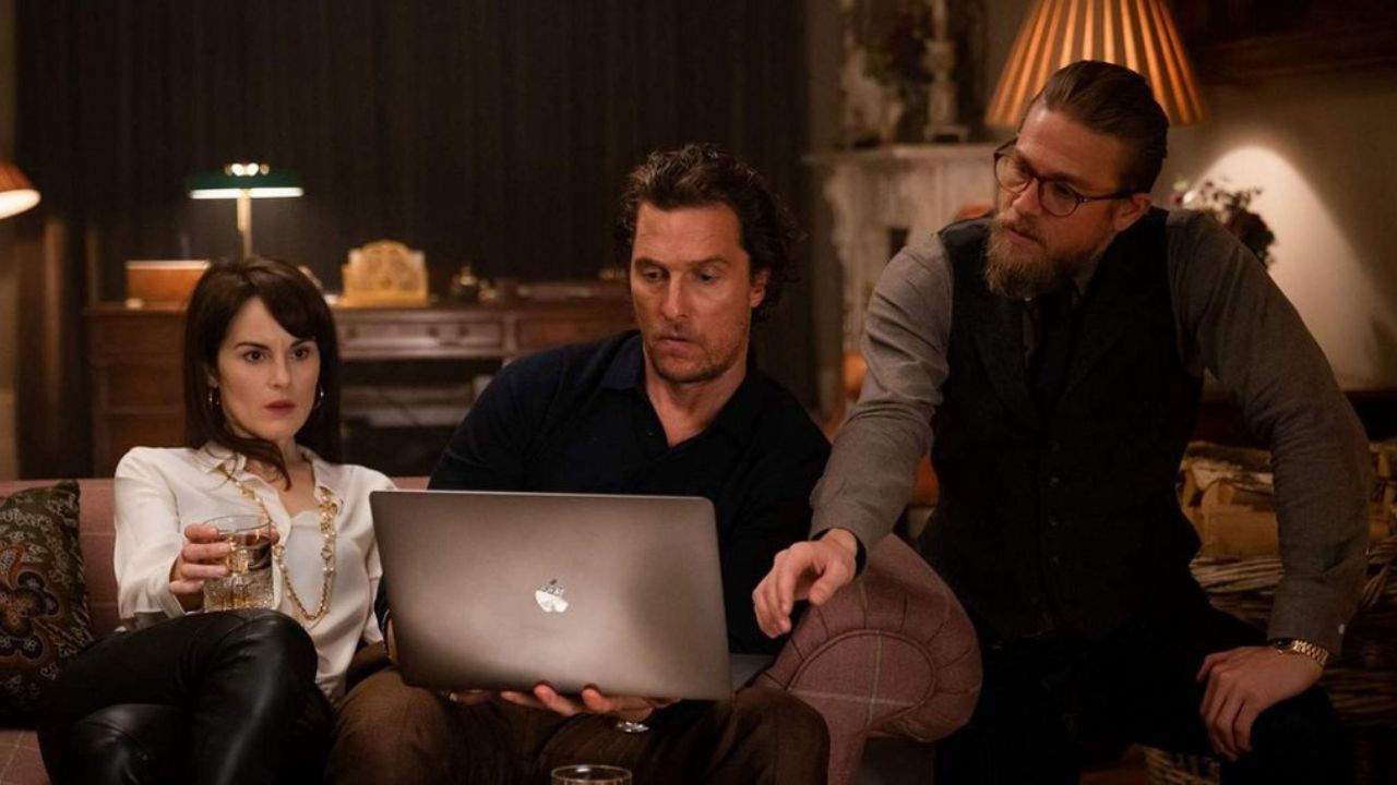 Michelle Dockery, Matthew McConaughey, and Charlie Hunnam looking at a laptop in The Gentlemen.