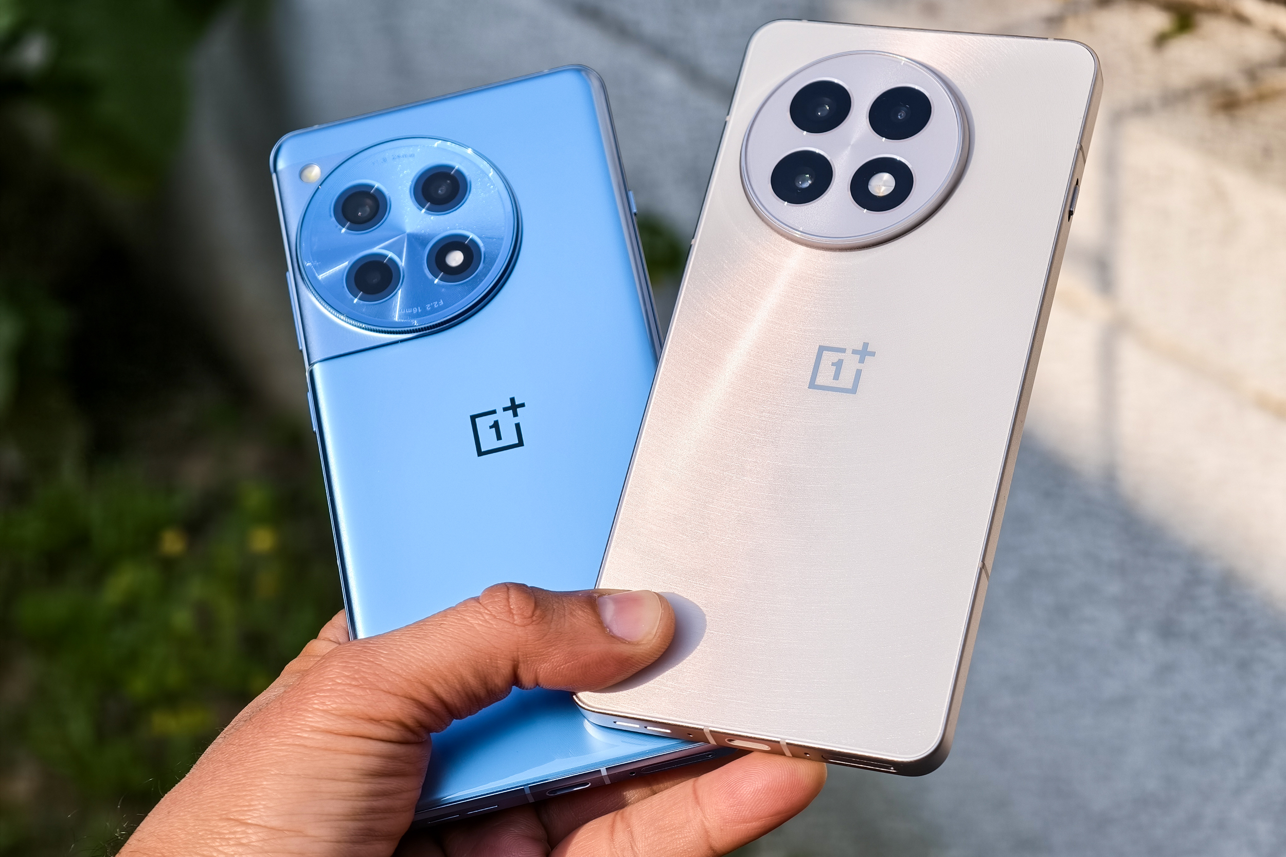 OnePlus 13R blanc et OnePlus 12R bleu tenus ensemble en main.