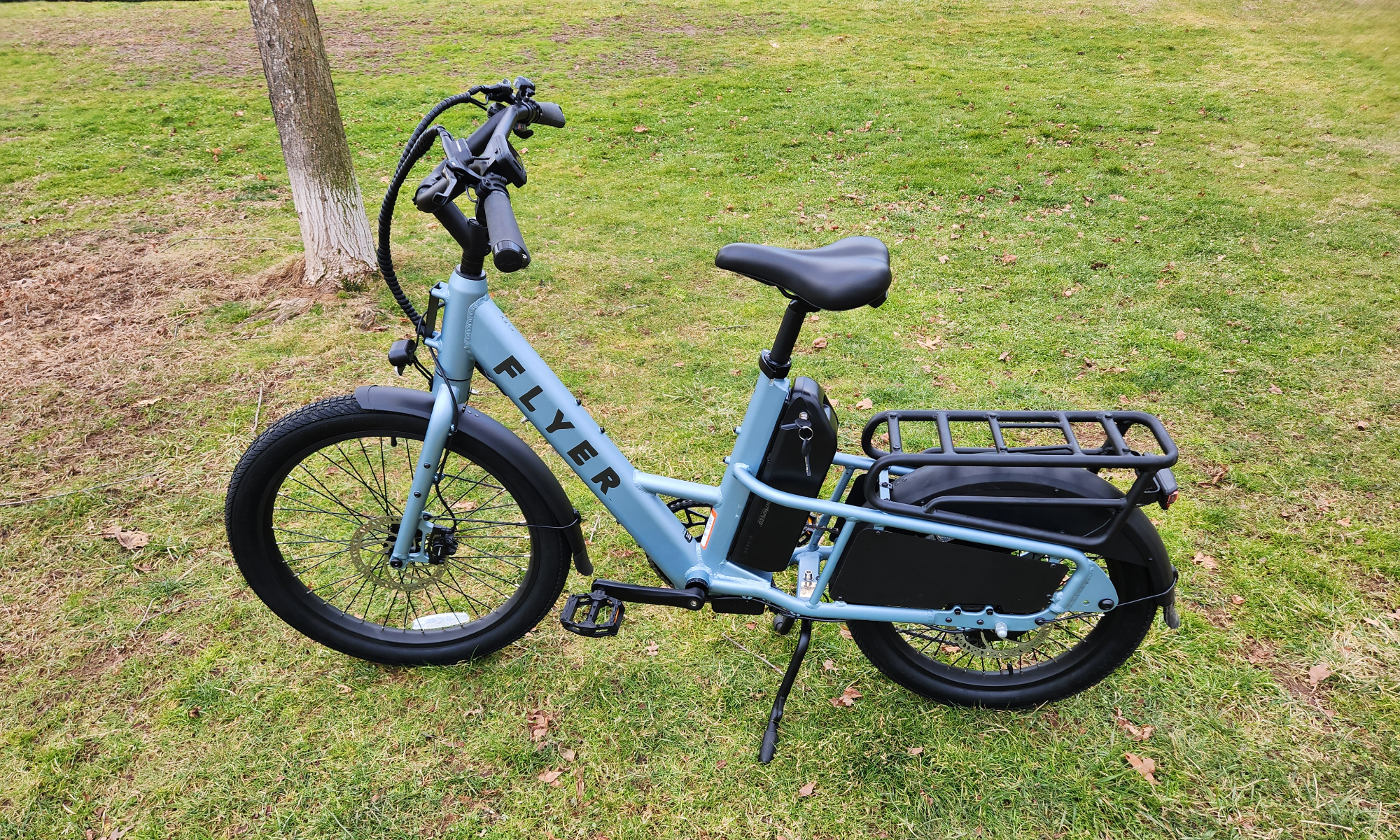 Bicicleta eléctrica Radio Flyer Flex en el lado izquierdo estacionada sobre el césped.