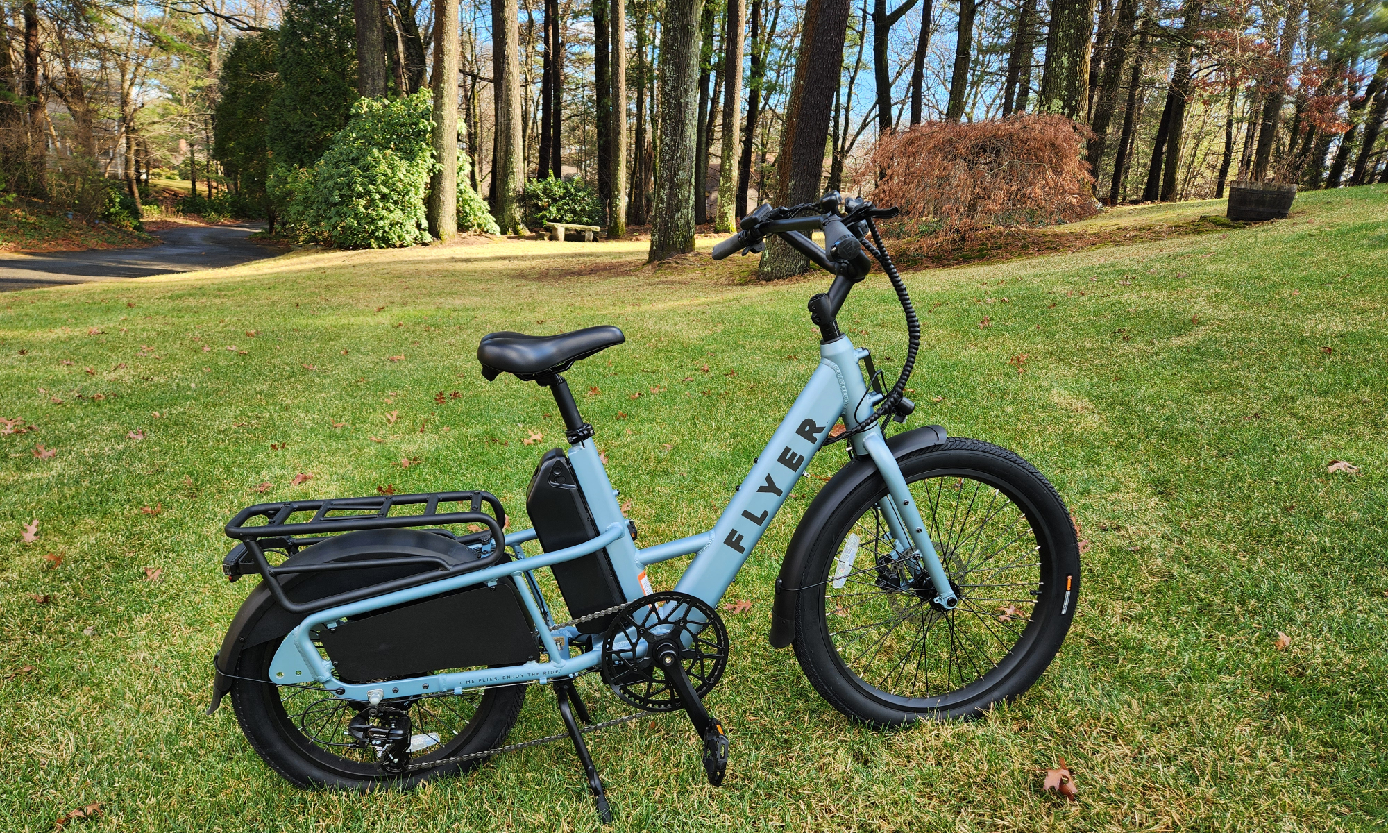 Vista lateral derecha de la bicicleta eléctrica Radio Flyer Flex sobre el césped con árboles al fondo.