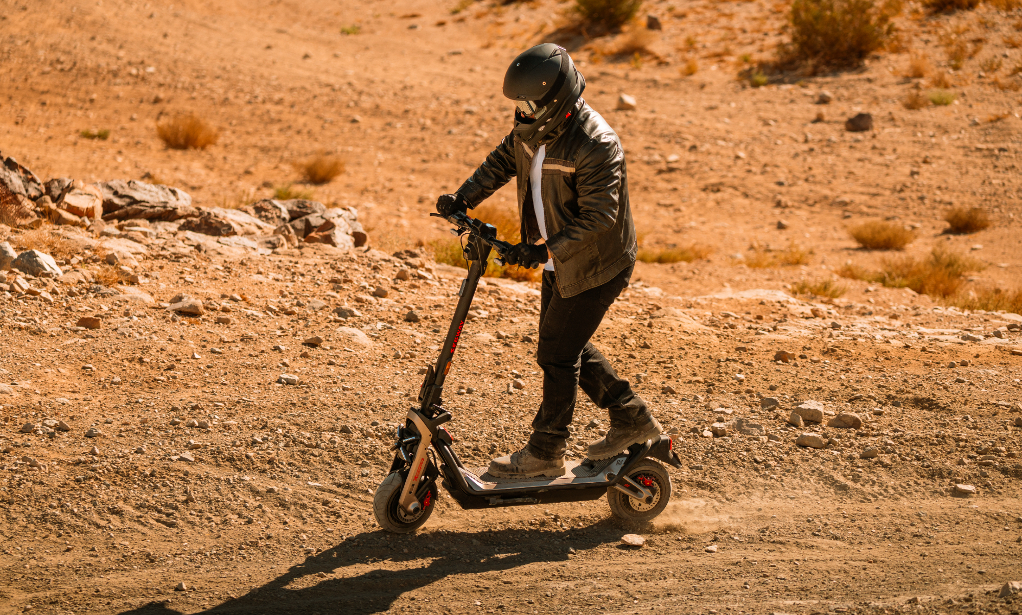 Pilote portant un casque, une veste en cuir et des bottes sur un Segway GT3 Pro dans le désert.